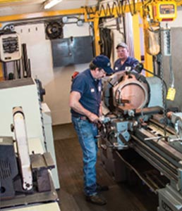 Two men work on a machine